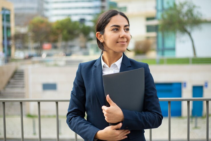 A smiling student holding a project file and posing to camera